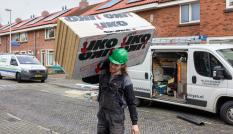 Bouwvakker loopt met isolatiemateriaal naar een huis